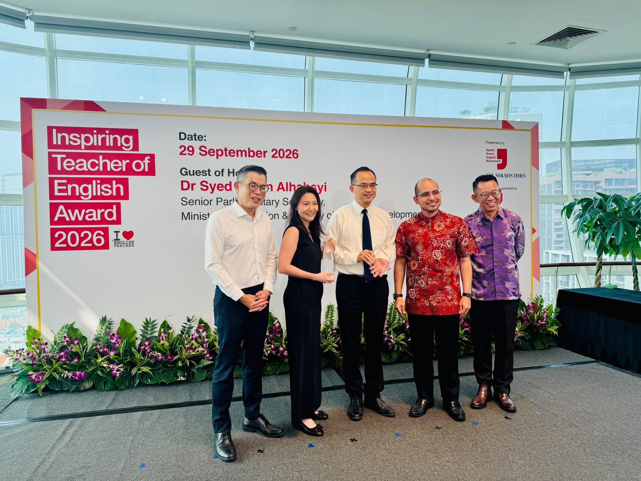 Five representatives posing on stage with trophy awards in front of a backdrop for the "Inspiring Teacher of English Award 2026" on 29 September 2026.